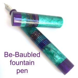 Green fountain pen with purple finials and section beaded with a range of bright colours